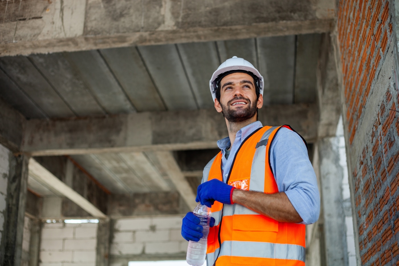 Construction worker holding water on a construction site.